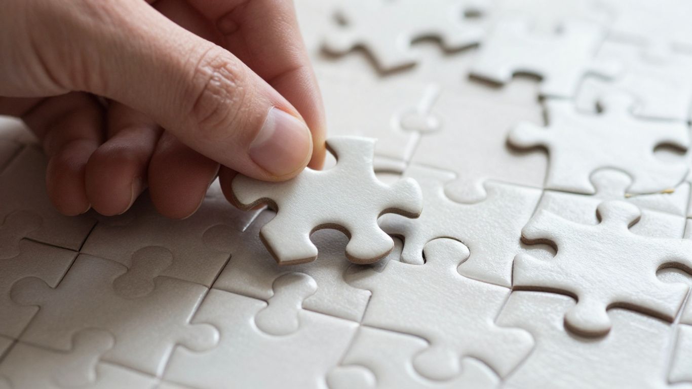Hand fügt Puzzleteil in komplexes Gebilde ein.